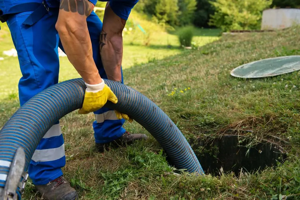 Septic service worker positioning a pumping hose at a tank opening