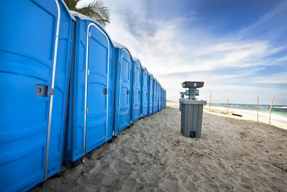 Row of portable toilets beside an outdoor handwash station
