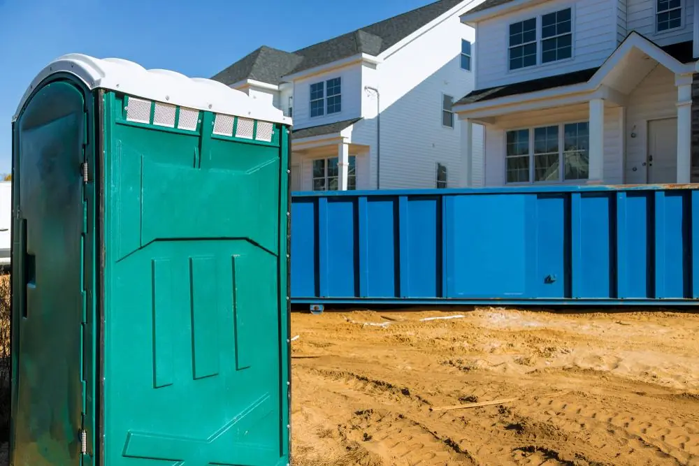 Portable toilet beside an active residential construction site
