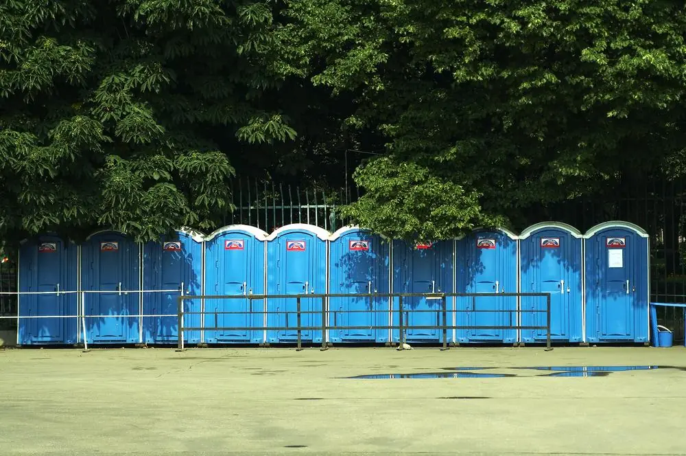 Four portable toilets arranged beside trees